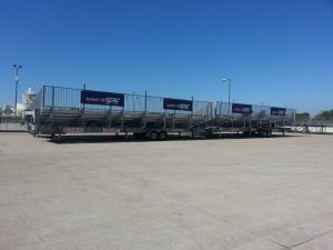 Extra large portable bleachers on asphalt with Red Bull sponsorship posters along back side guardrail