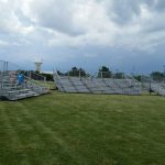 Three large portable bleachers fully extended and setup on grass field