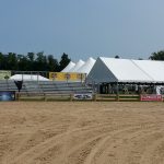 Metal bleachers with sponsorship posters setup alongside white tent for an Ohio outdoor show