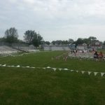 Setup for portable bleachers on a field with American flags lining chairs